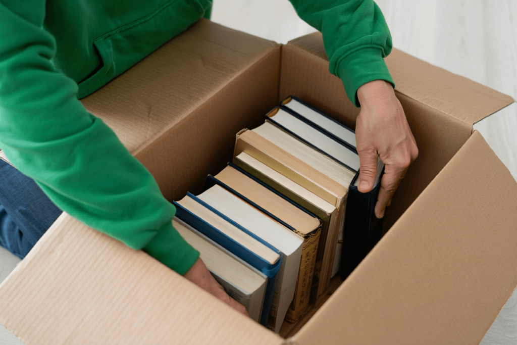 человек складывает книги в коробку